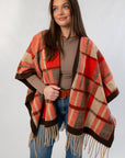 Fireside Plaid Shawl in cozy orange and brown tones with fringe detail, styled over a taupe top and jeans for fall fashion.