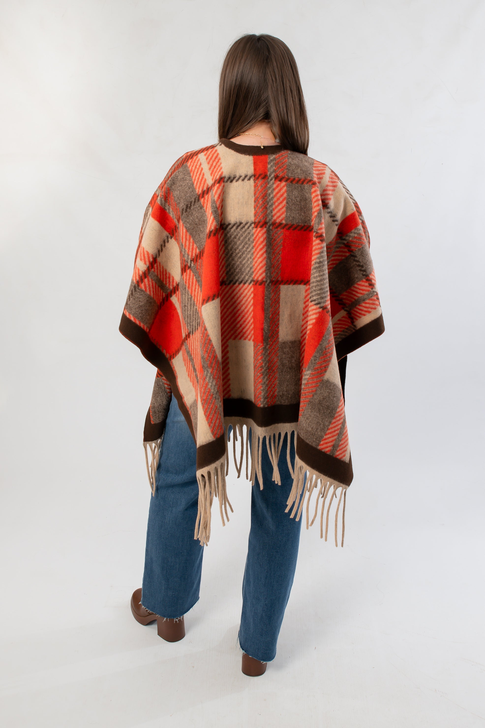 Back view of Fireside Plaid Shawl highlighting its bold orange plaid design and soft fringe, styled for autumn comfort and charm.