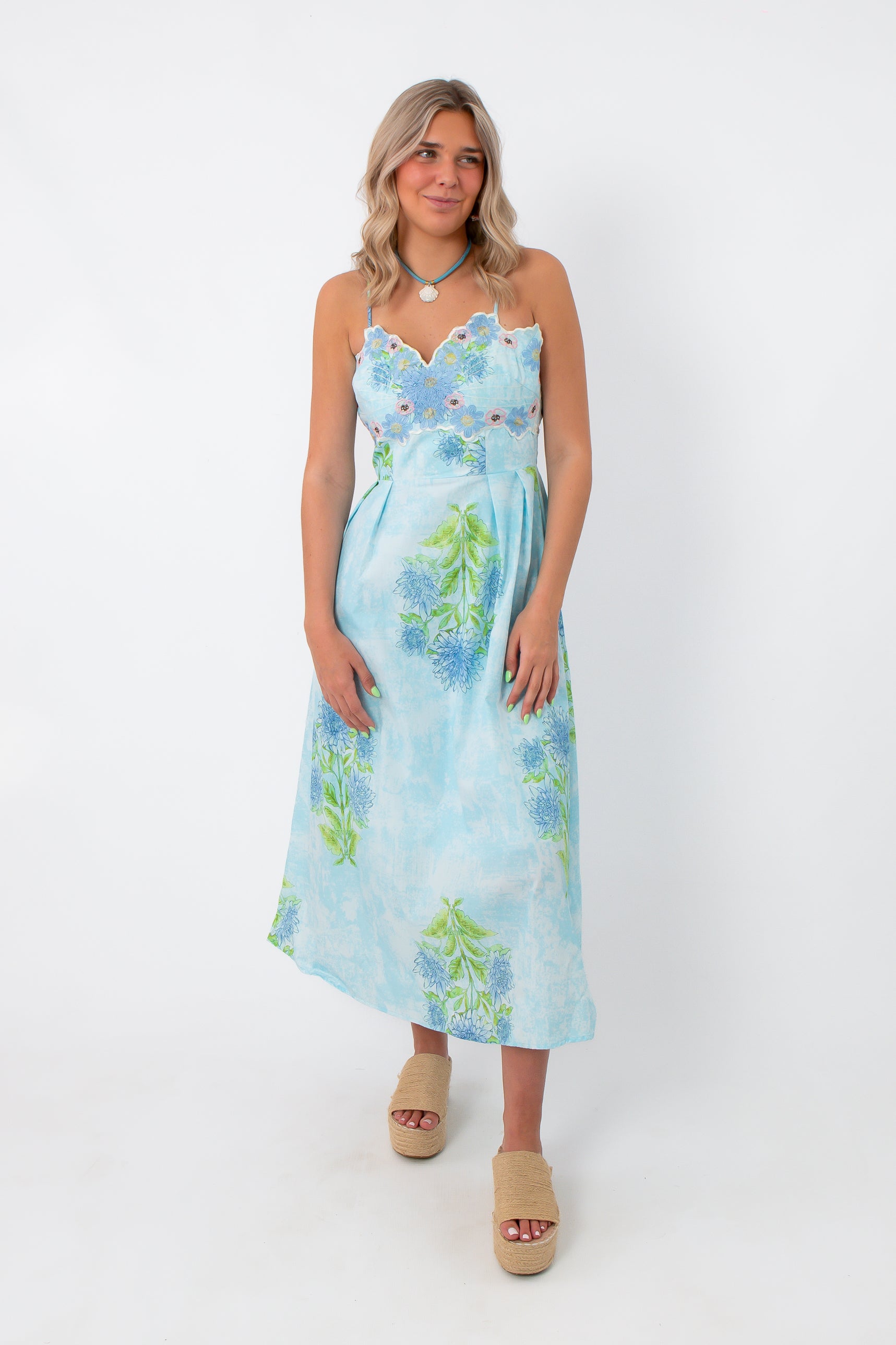 Allium Field Floral Embroidered Midi Dress with blue floral embroidery, spaghetti straps, and a low back, styled with beige platform sandals