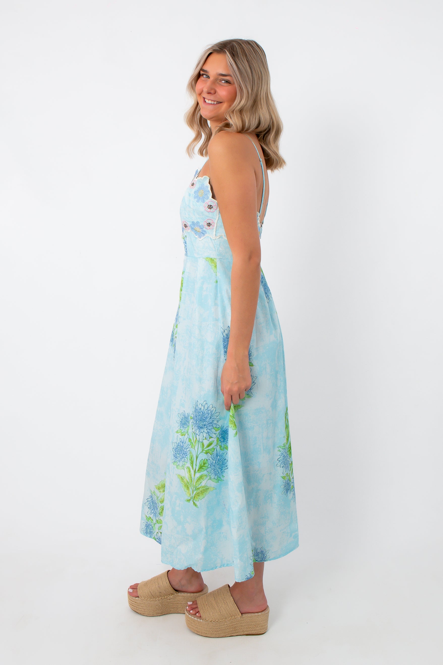 Side view of Allium Field Floral Embroidered Midi Dress featuring blue and green floral print, with a fitted bodice and flowing skirt