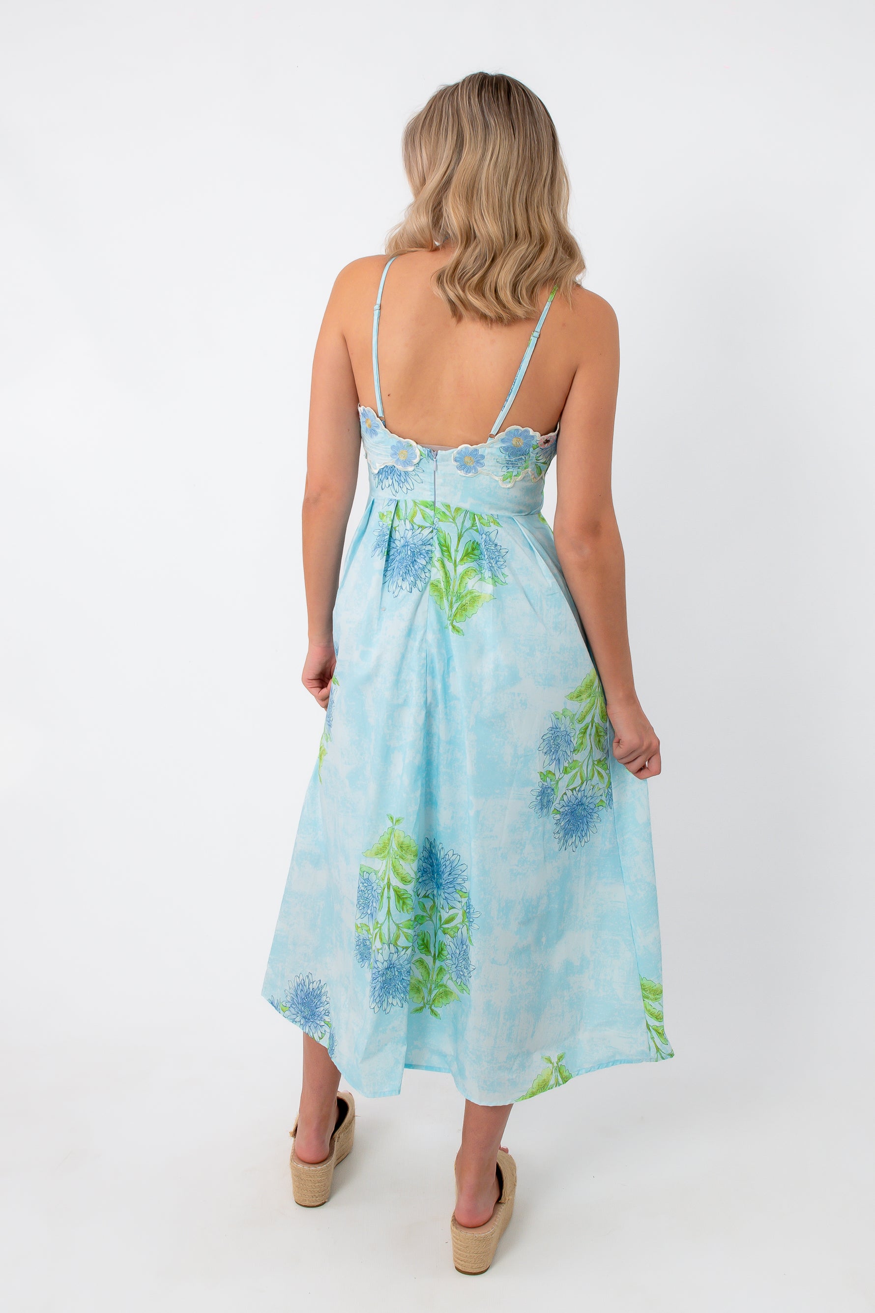 Back view of Allium Field Floral Embroidered Midi Dress with floral print, spaghetti straps, and flowing hemline, styled with platform sandals