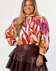 Woman wearing a colorful blouse and brown leather skirt on a white background
