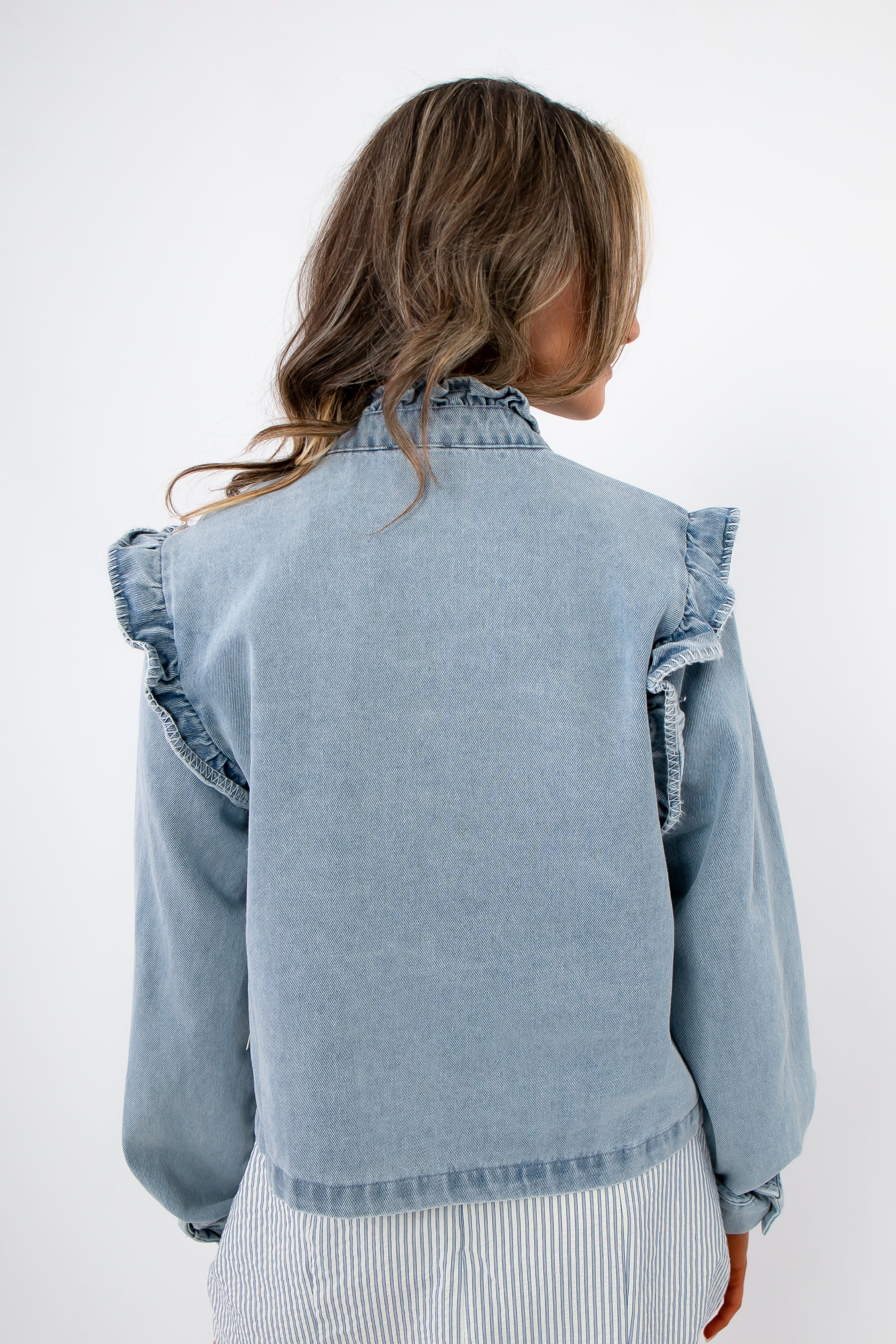 Back view of Ruffle-Trim Light Wash Denim Jacket with shoulder ruffles and light wash finish, a chic women’s outerwear piece for casual looks.