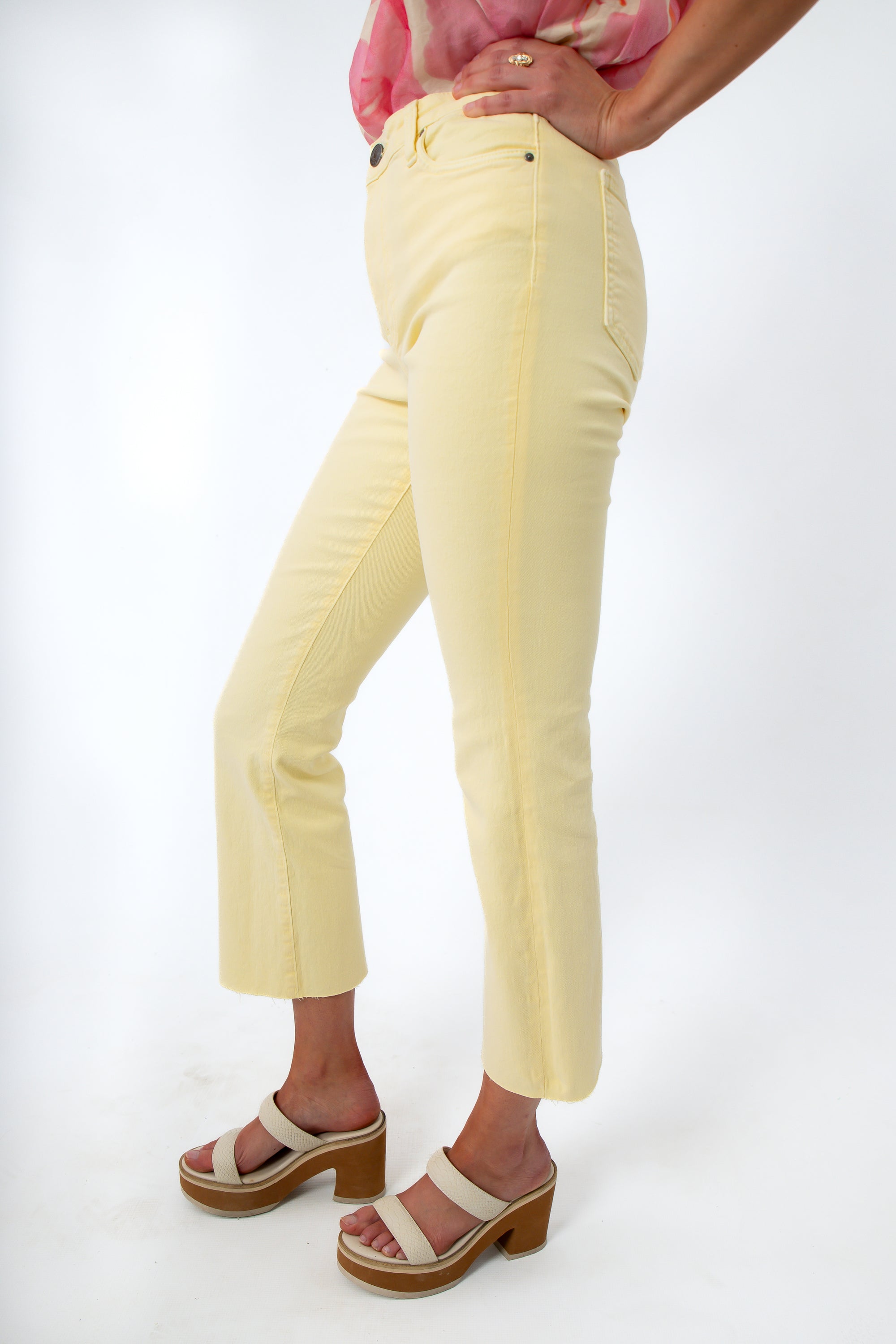 Back view of pastel yellow jeans with rear pockets, styled with pink floral top and platform sandals