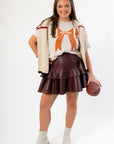 Game Fashion look featuring the Goal Line Football Tee with bone bow print, layered with a sweater and styled with boots and a leather skirt.