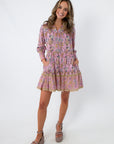 Long sleeve floral mini dress with pink and purple pattern, collared neckline, and pockets, styled with platform heels