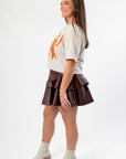 Side view of the Goal Line Football Tee styled with a maroon ruffle skirt and ankle boots, showcasing a casual yet chic game day look.