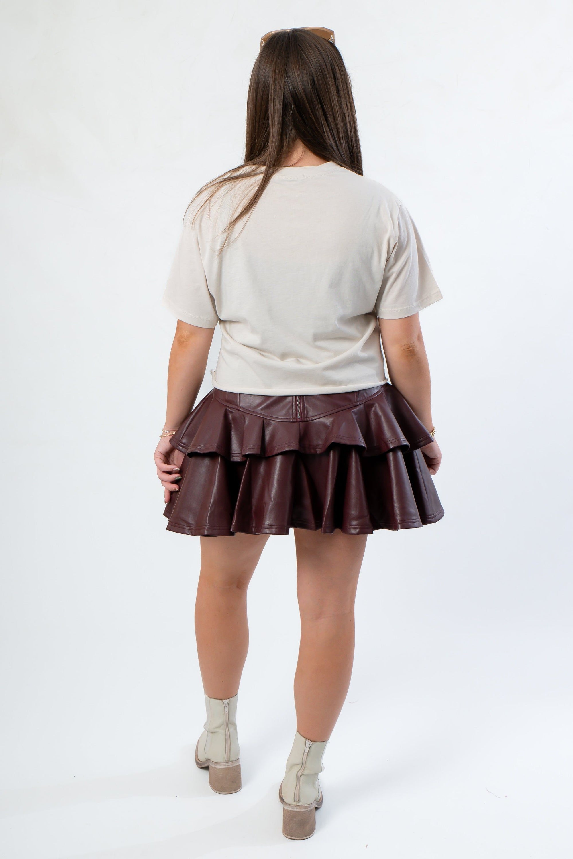 Back view of the Bone Bow Football Crop Tshirt and maroon leather skirt, highlighting the relaxed fit and layered design for game day fashion.