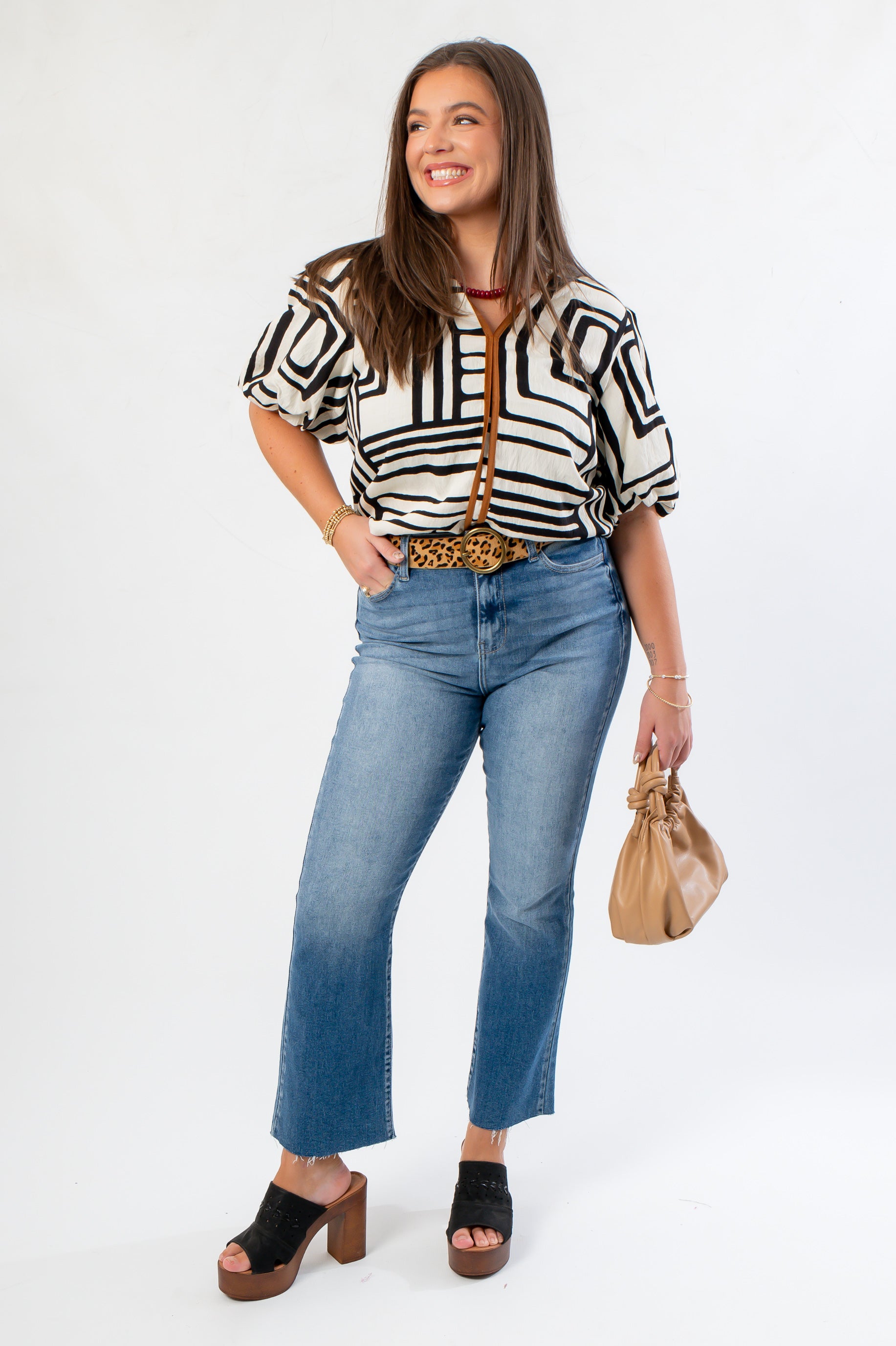 Medium Wash High Rise Crop Flare Jeans styled with a bold patterned top and platform heels. Features a raw hem and flattering high-rise fit.