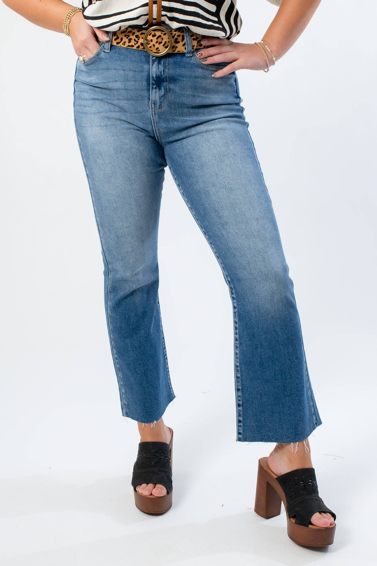 Close-up of Medium Wash High Rise Crop Flare Jeans showcasing raw hemline and kick flare design. Ideal for casual and chic outfits.
