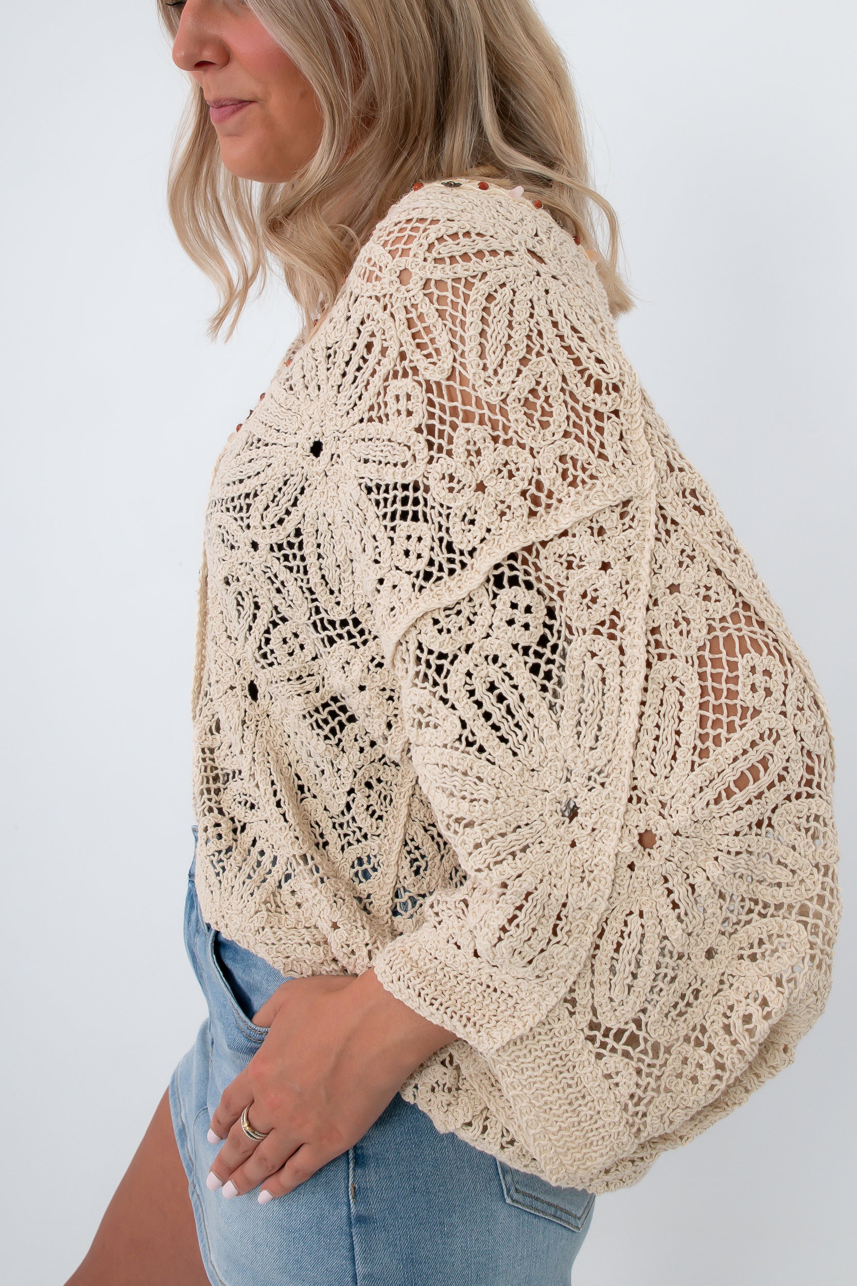 Back view of beige crochet coverup cardigan with floral design, beachwear