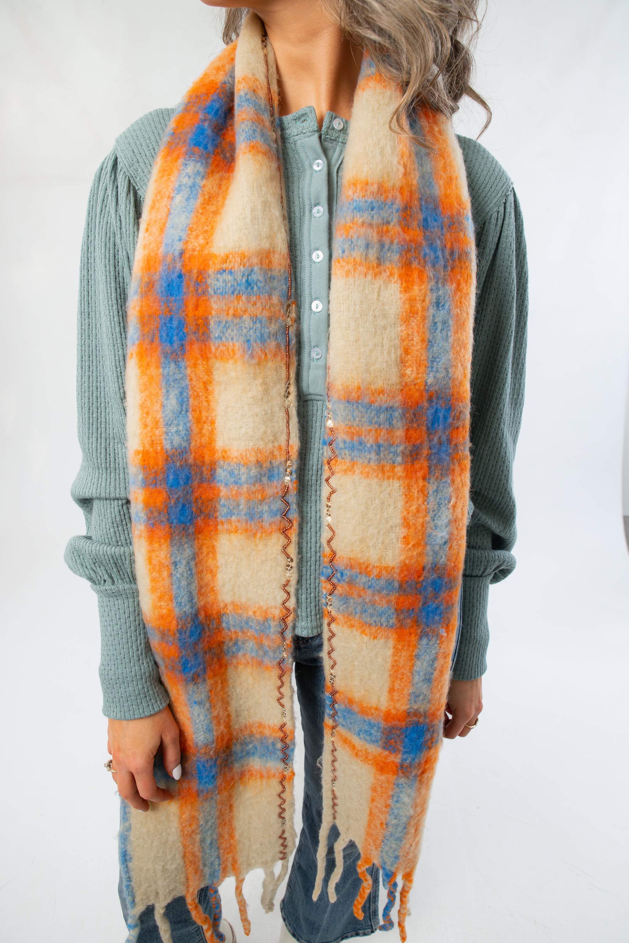 Close-up of Highland Plaid Skinny Scarf by Free People featuring soft texture and vibrant orange and blue plaid pattern, ideal for fall fashion.