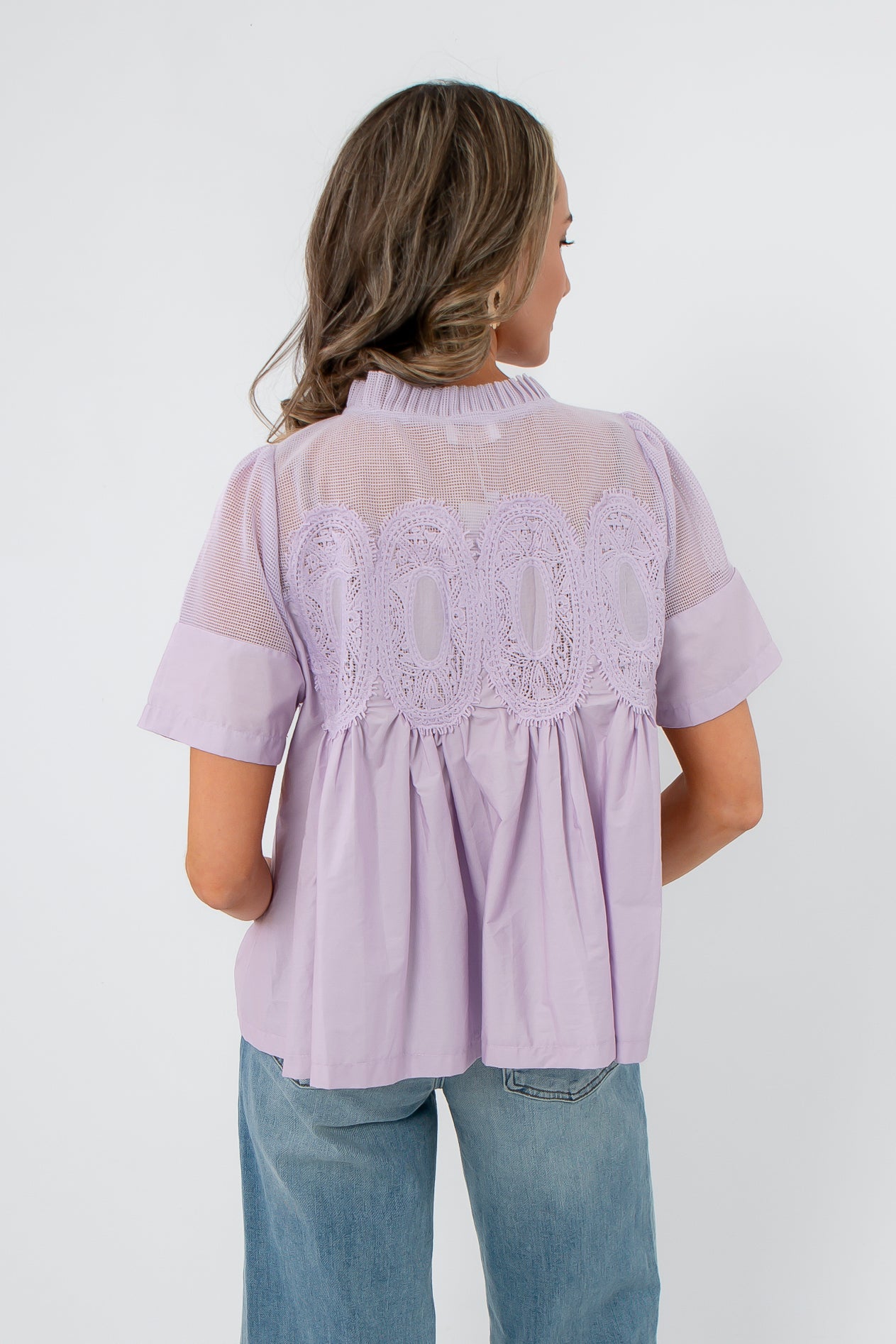 Back view of Lacy Lavender Mesh Babydoll Blouse highlighting pleated design and sheer mesh panel for a feminine spring look.