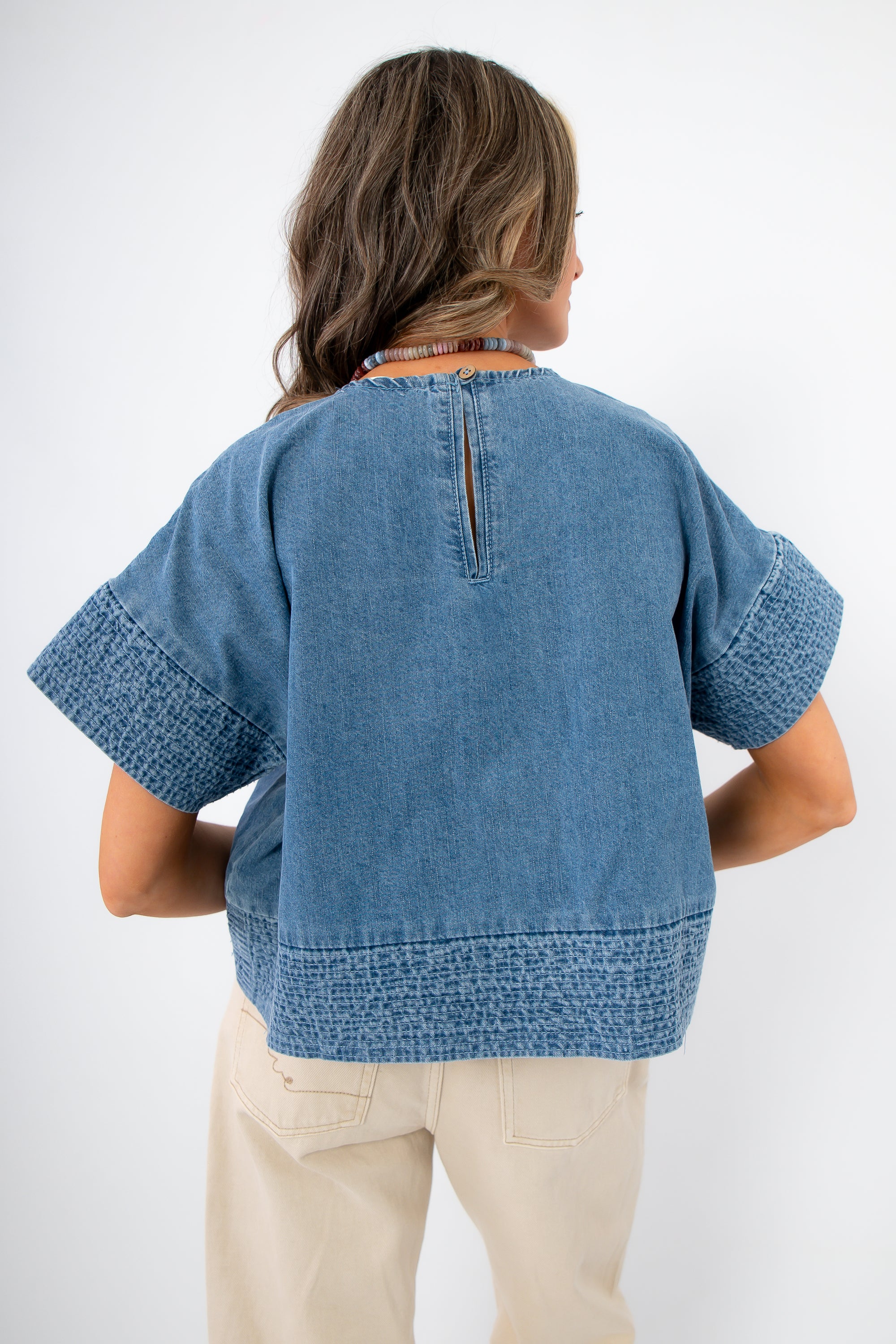 Indigo Daydream Chambray Denim Top | Back view showing keyhole button closure and textured hem, a trendy addition to any denim wardrobe.