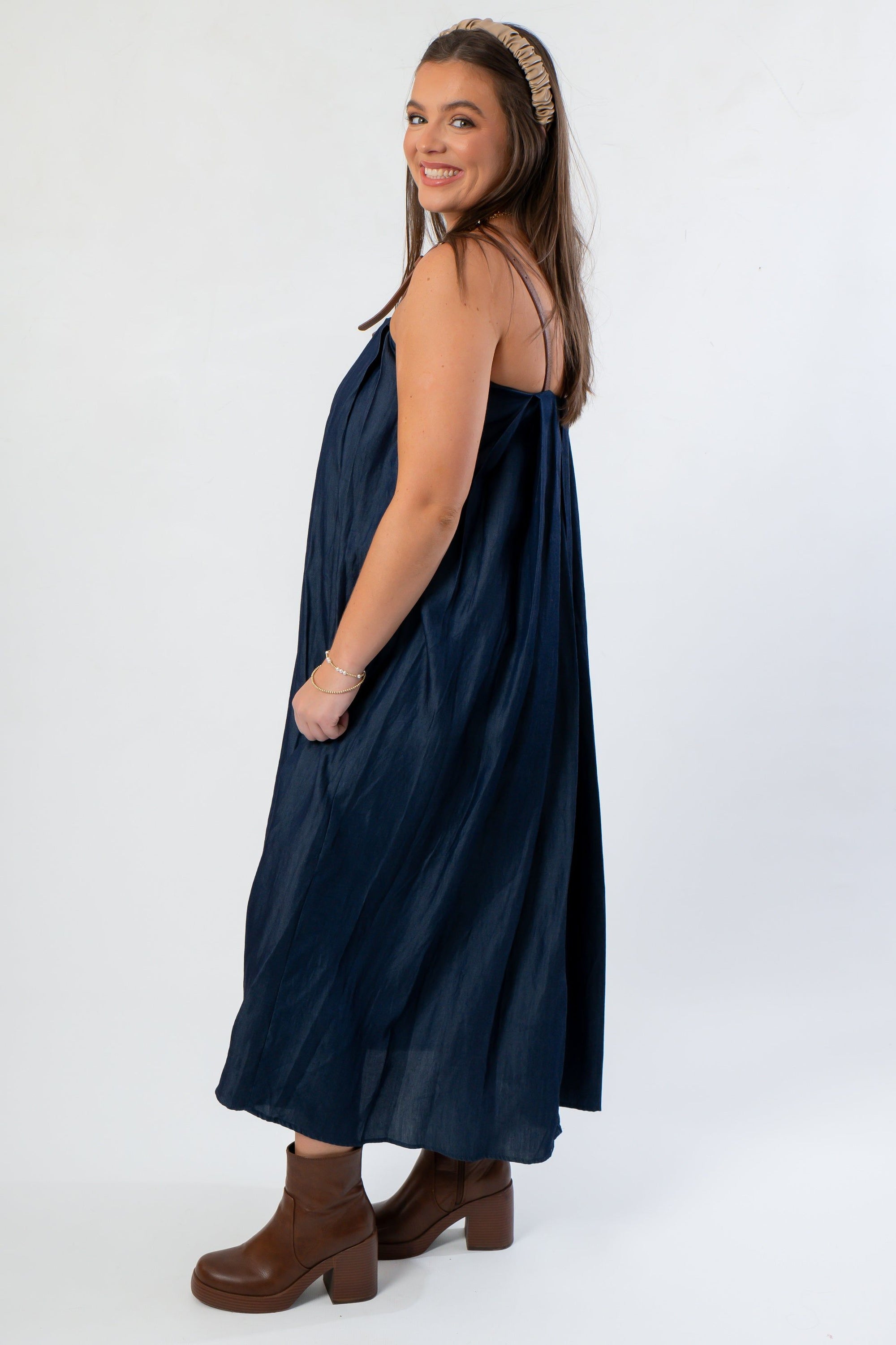 Side profile of THML Denim Buckle Strap Dress highlighting its flowy midi length and soft denim texture, perfect for fall fashion.