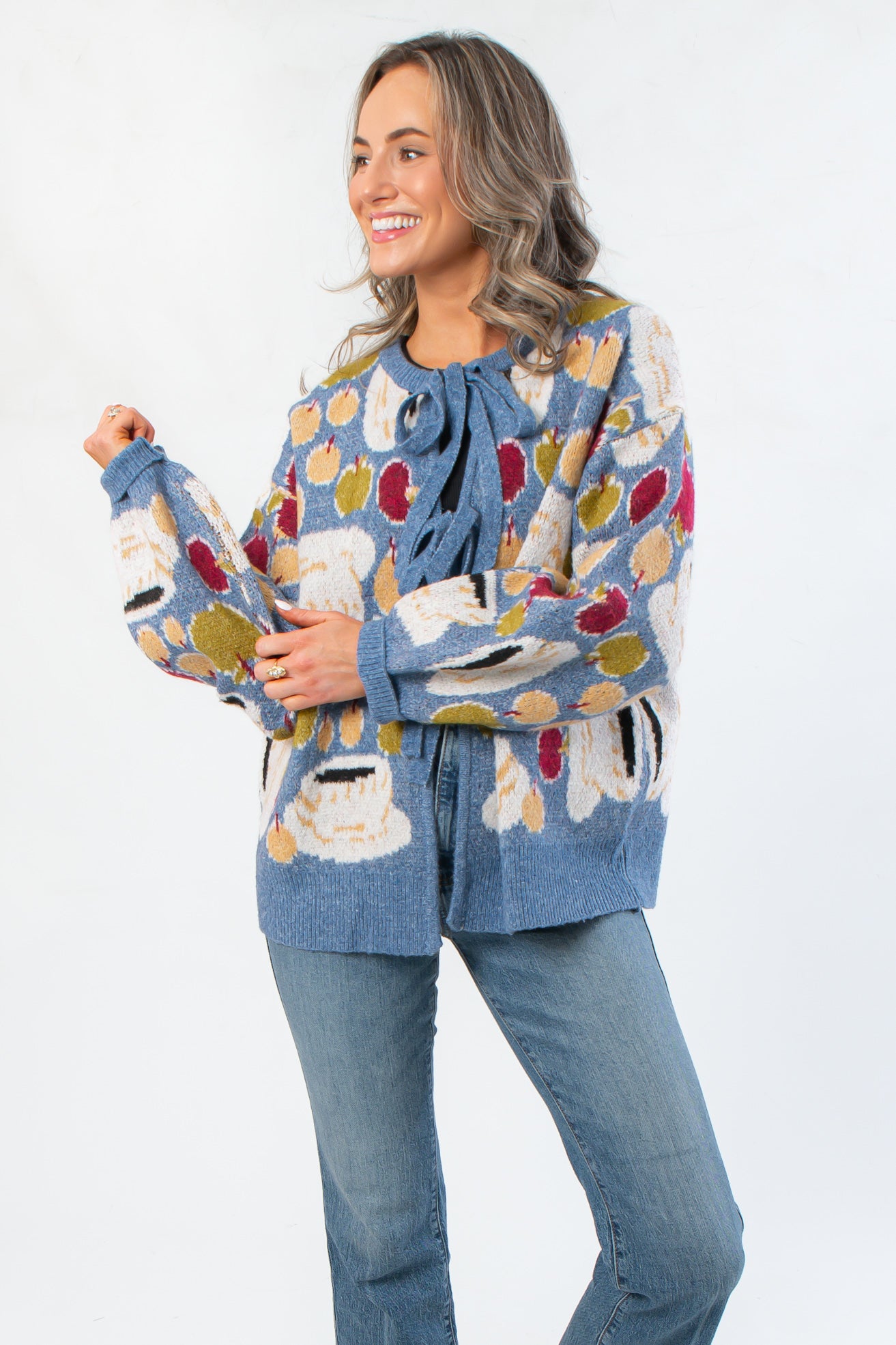 Apple A Day Blue Tie Front Cardigan with oversized apple print and front bow tie, styled with jeans for a cozy fall look.