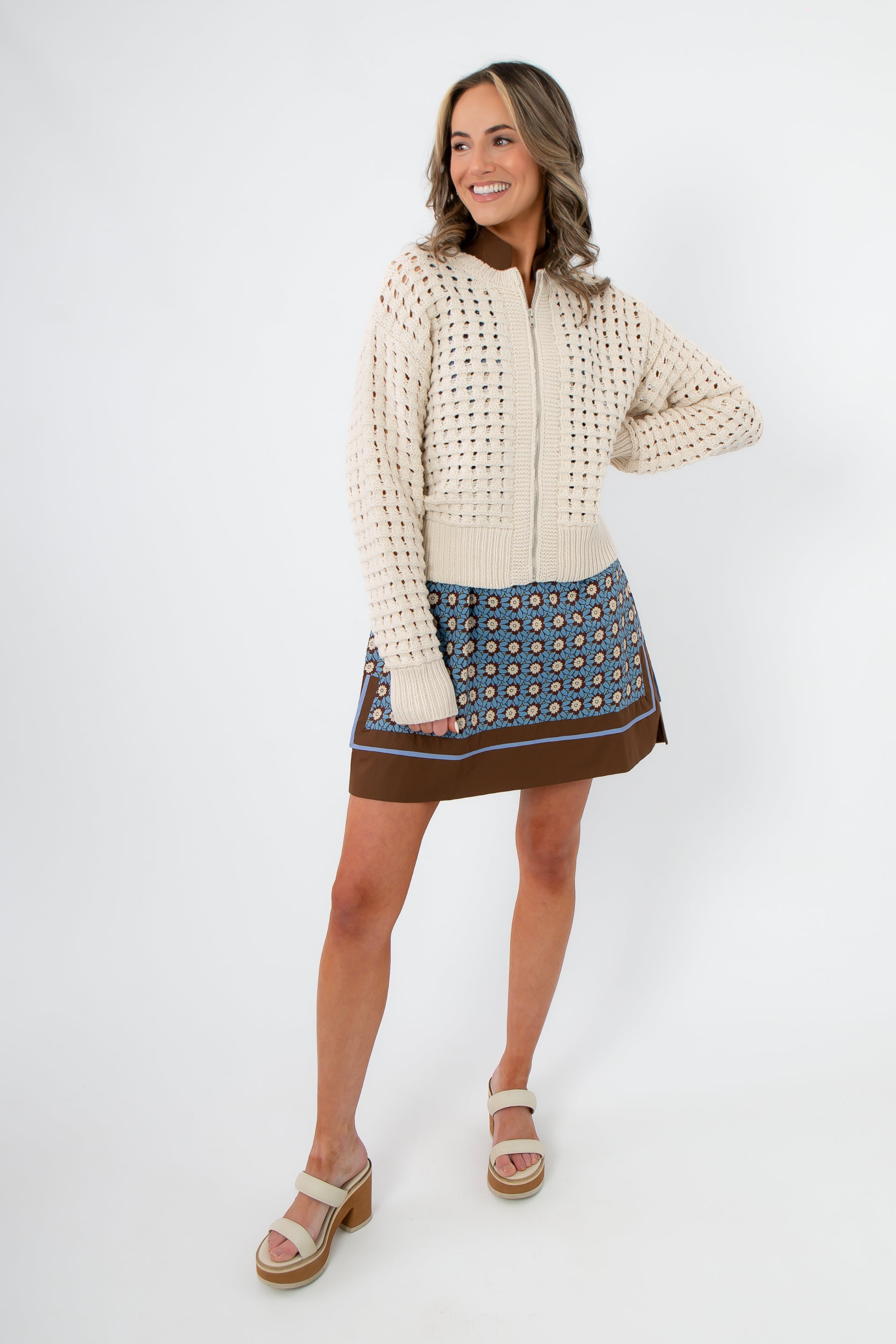 Z Supply Crystal Logan Sweater Jacket in cream, styled with a floral mini skirt for cozy spring layering. Lightweight knit perfect for transitional weather.