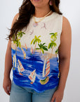 Close-up of woman in tropical sailboat print sleeveless top with palm trees and sailboats, smiling