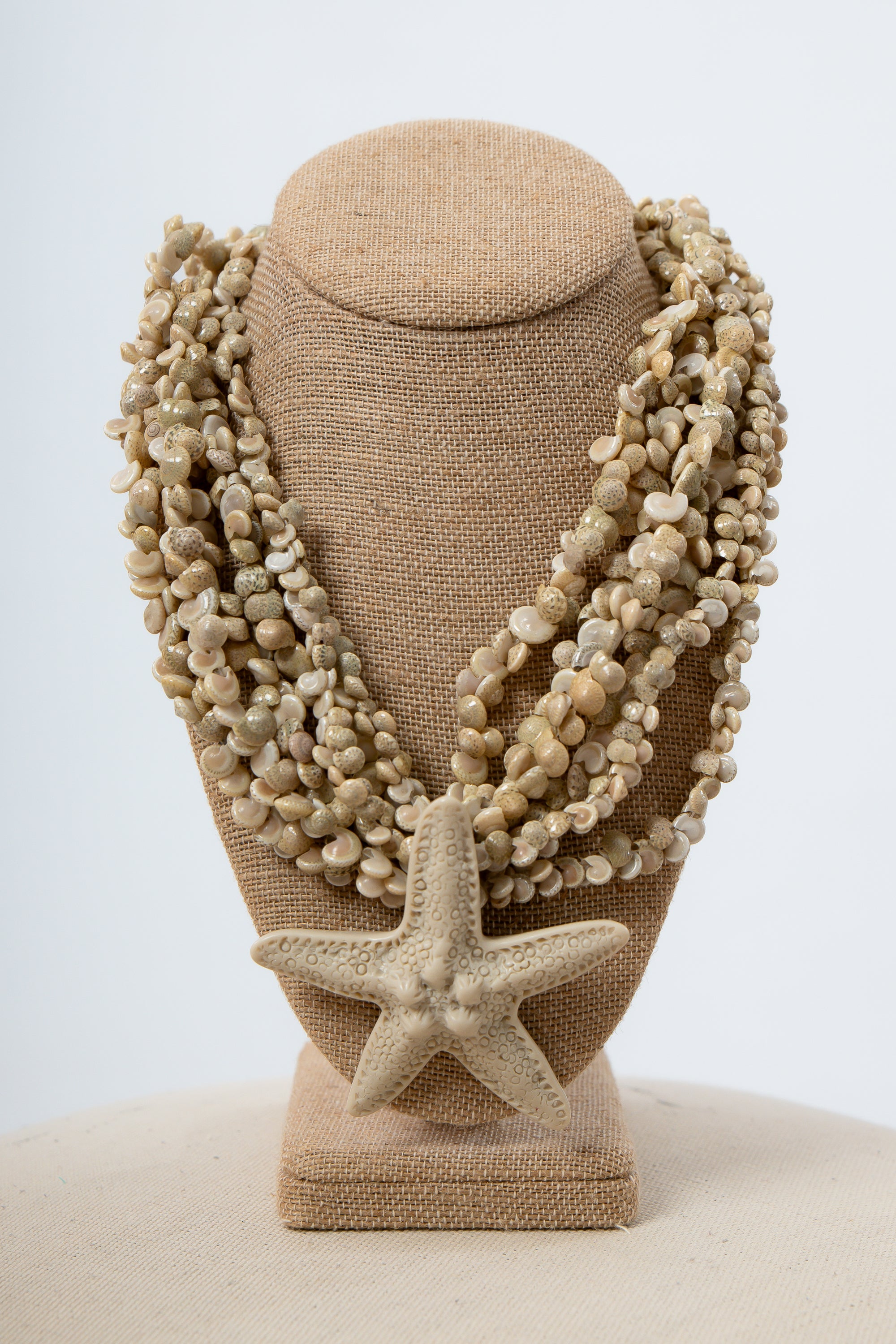 Beige starfish and seashell statement necklace with sandy pebble beads on display