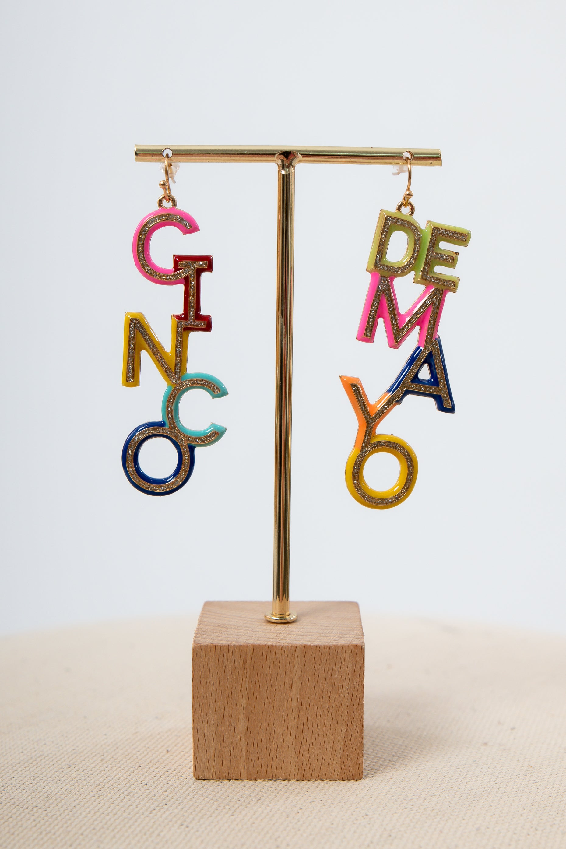 Colorful letter earrings on display stand