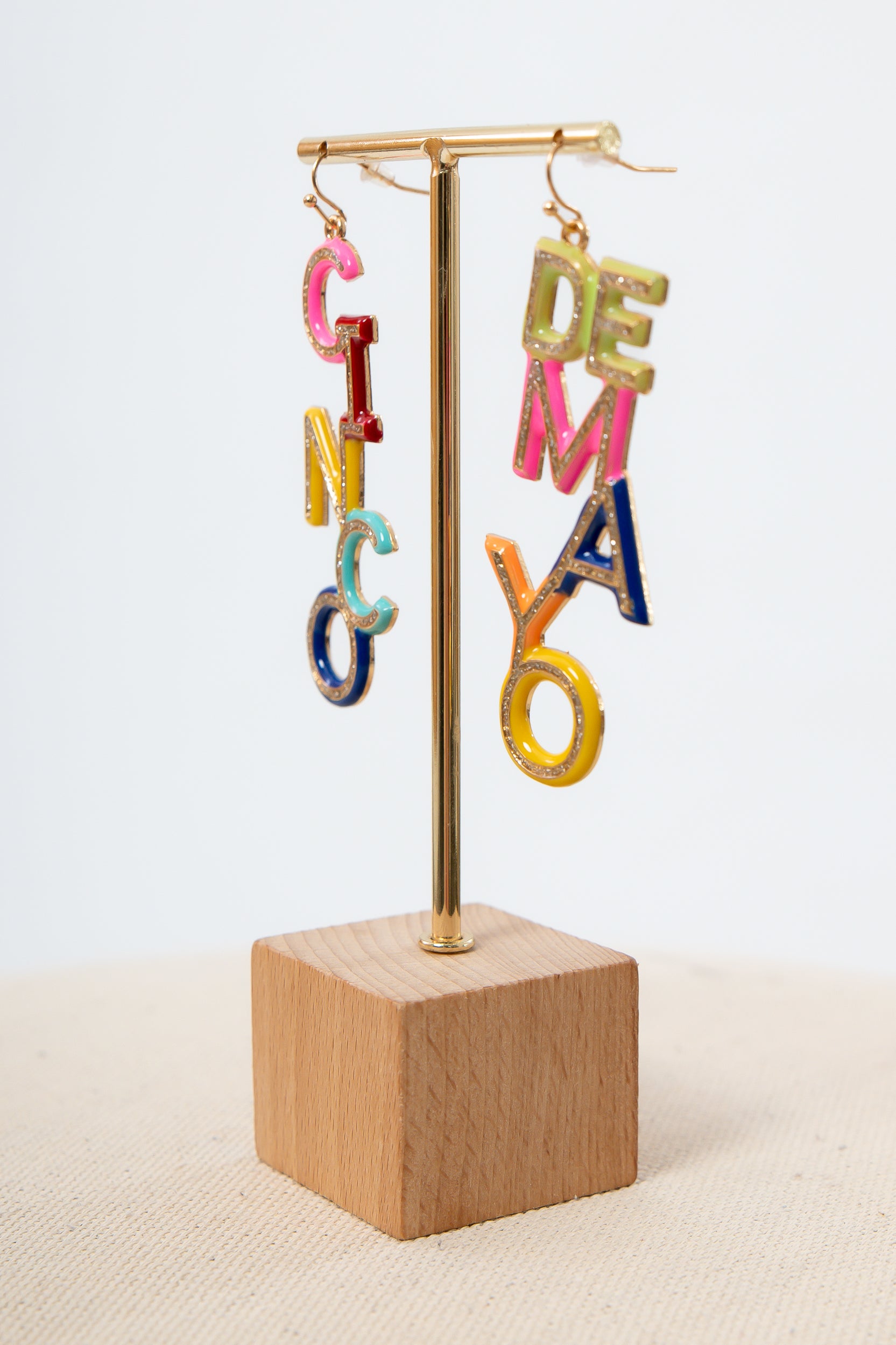 Colorful letter earrings on display stand