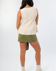 Champagne Flared Rib Knit Top – Back view of ribbed knit sleeveless top featuring flared hem, styled with olive skirt and neutral boots.