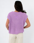 Back view of Wisteria Willow Short Sleeve Lilac Sweater featuring a patch detail and loose fit, a trendy pastel top for warm-weather layering.