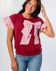 Red Burgundy Knit Top featuring a large pink bow and ruffled sleeves, perfect for gameday or holiday outfits with a soft, warm texture.