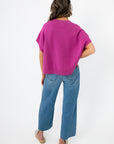 Back view of Whatever The Weather Orchid Sleeveless Sweater highlighting ribbed hem and relaxed silhouette. Chic purple knit top for modern wardrobes.