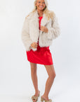 Boutique Winter Wonderland Ivory Faux Fur Jacket paired with a red dress and heels. Elegant women's outerwear for Christmas or wedding guest looks.