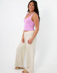 Side profile of Free People Pale Orchid Clean Lines Muscle Cami-Stylish & Comfortable Sleeveless Top, styled with relaxed striped pants.