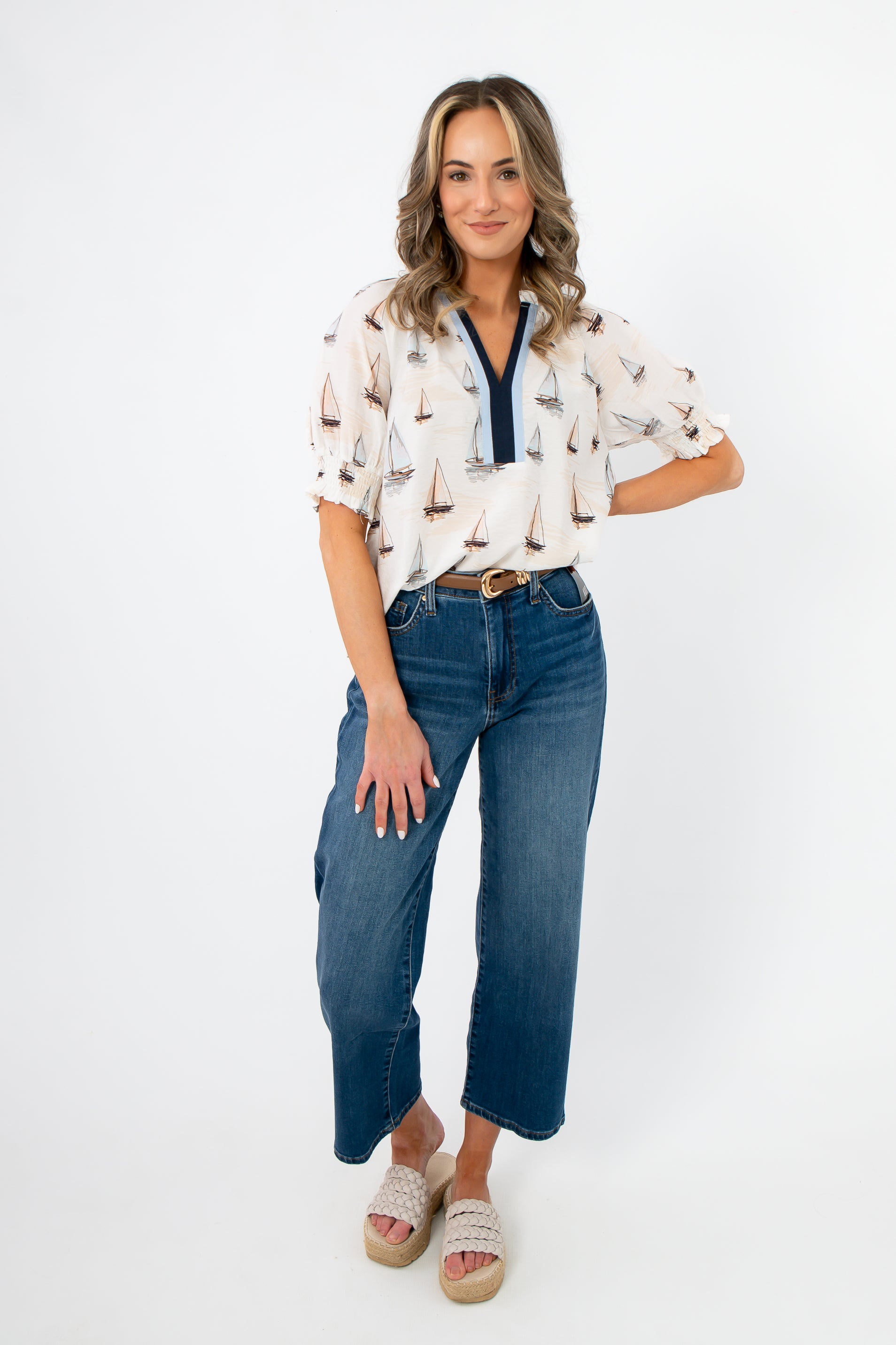 Woman wearing a patterned blouse and blue jeans on a white background