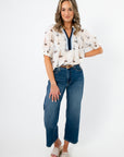 Woman wearing a patterned blouse and blue jeans on a white background