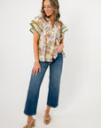 Ecru floral ruffle sleeve blouse styled with wide-leg jeans and heeled sandals, perfect for spring events or casual outings.