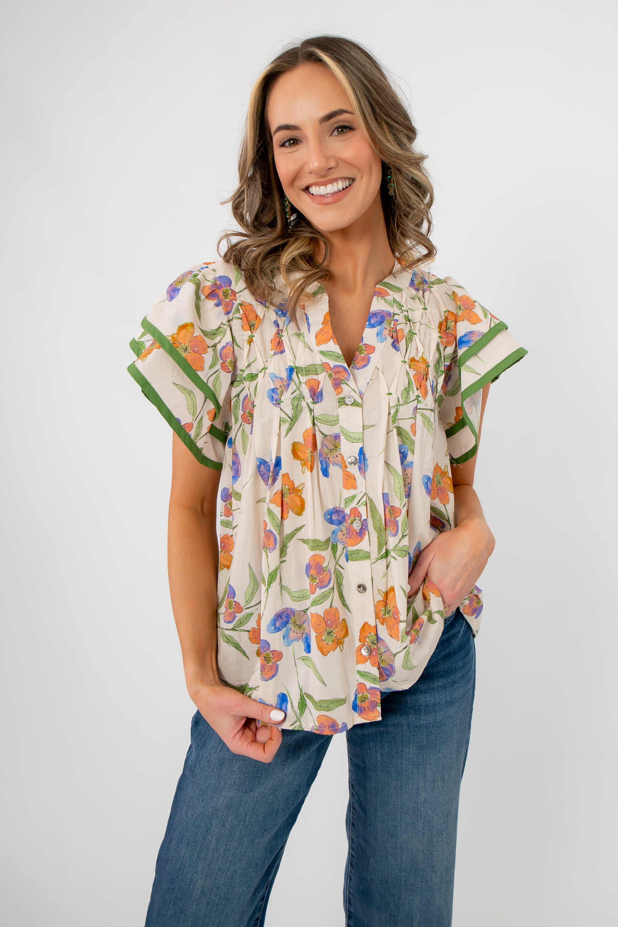 Spring Fling Floral Ruffle Sleeve Blouse in ecru with colorful floral print and green-trimmed ruffle sleeves, styled with blue jeans.