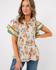 Model wearing Spring Fling Floral Ruffle Sleeve Blouse with relaxed fit and flutter sleeves, ideal for spring and summer styling.