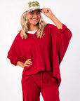 Free People Deep Cherry Staycation Pullover – Cozy oversized V-neck sweatshirt in rich red, styled with matching lounge pants for a relaxed look.