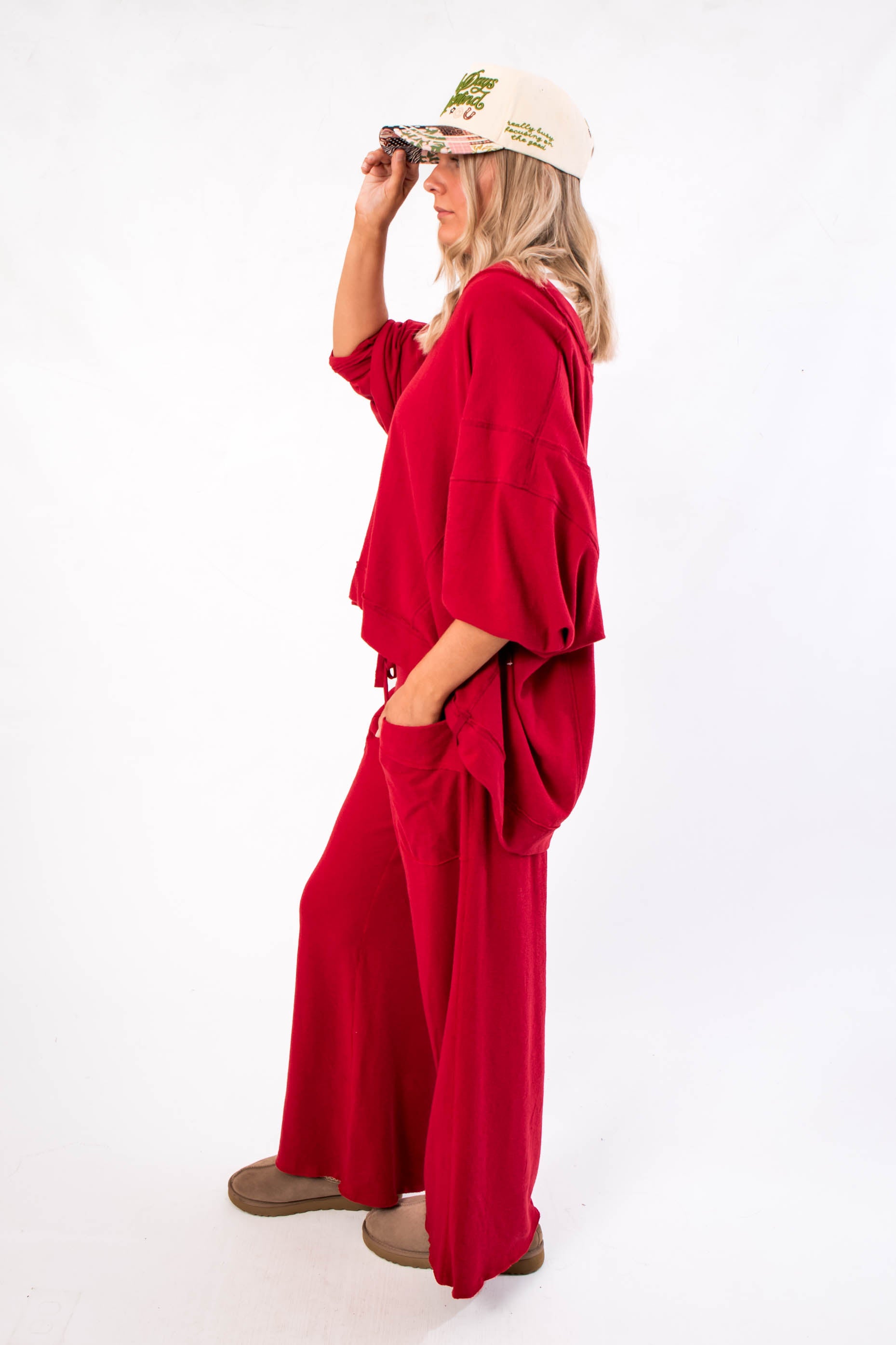 Free People Deep Cherry Staycation Pullover – Side view of loose-fit V-neck top in deep cherry, showcasing draped sleeves and cozy texture.