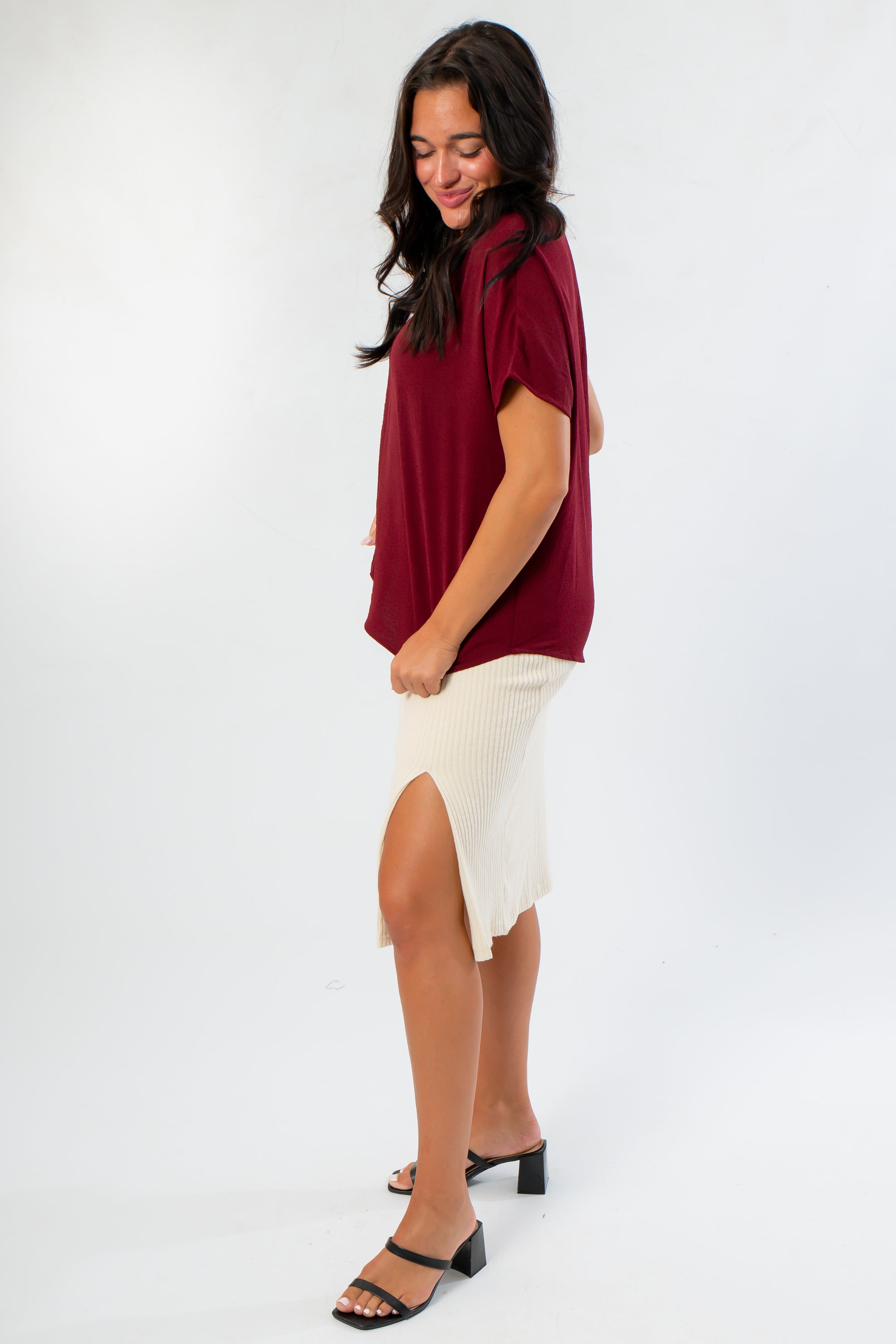 Side view of Burgundy Short Sleeve Blouse and cream ribbed skirt with slit, offering a chic and comfortable outfit for gameday or casual outings.