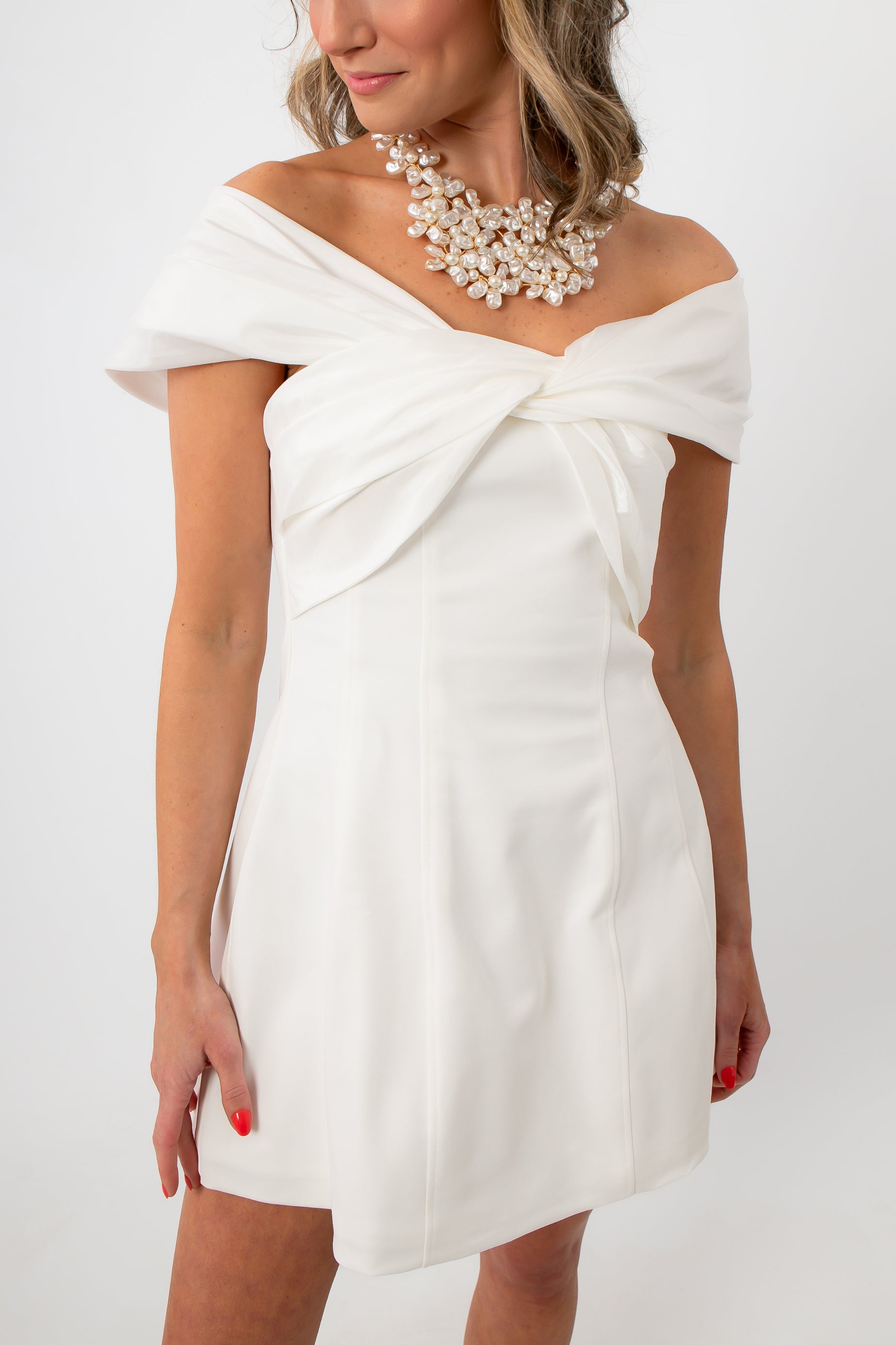 Model in white off-shoulder mini dress with statement pearl necklace for special events