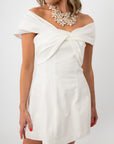 Model in white off-shoulder mini dress with statement pearl necklace for special events