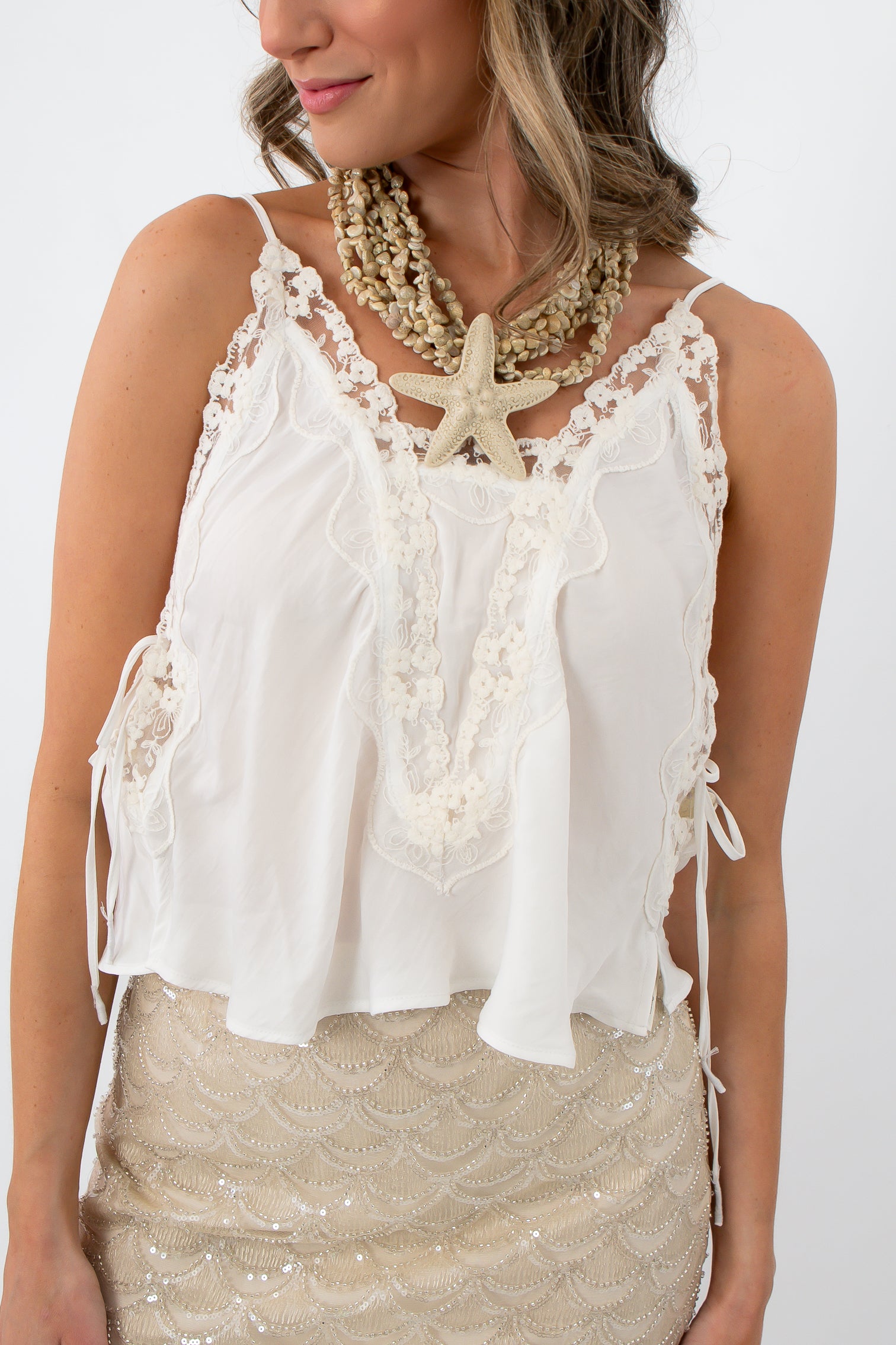 Close-up of lace details and side ties on ivory camisole top