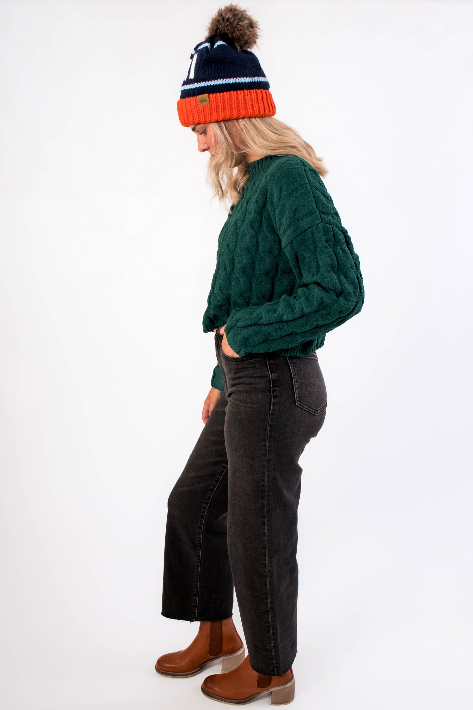 Side view of Tree Farm Stroll Cable-Knit Sweater showcasing its thick cable-knit design and cropped hem, ideal for winter layering.