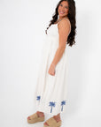 MINKPINK Isadora Palm Embroidered Midi Dress in white with blue palm tree embroidery, featuring adjustable straps and a flowy silhouette.