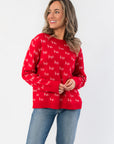 Ho Ho Ho-liday Cheer Red Christmas Sweater with white 'ho' text pattern, long sleeves, and ribbed hem, styled with denim jeans.