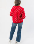 Back view of red Christmas sweater with repeating 'ho' print, ribbed cuffs and hem, styled for a cozy boutique holiday look.