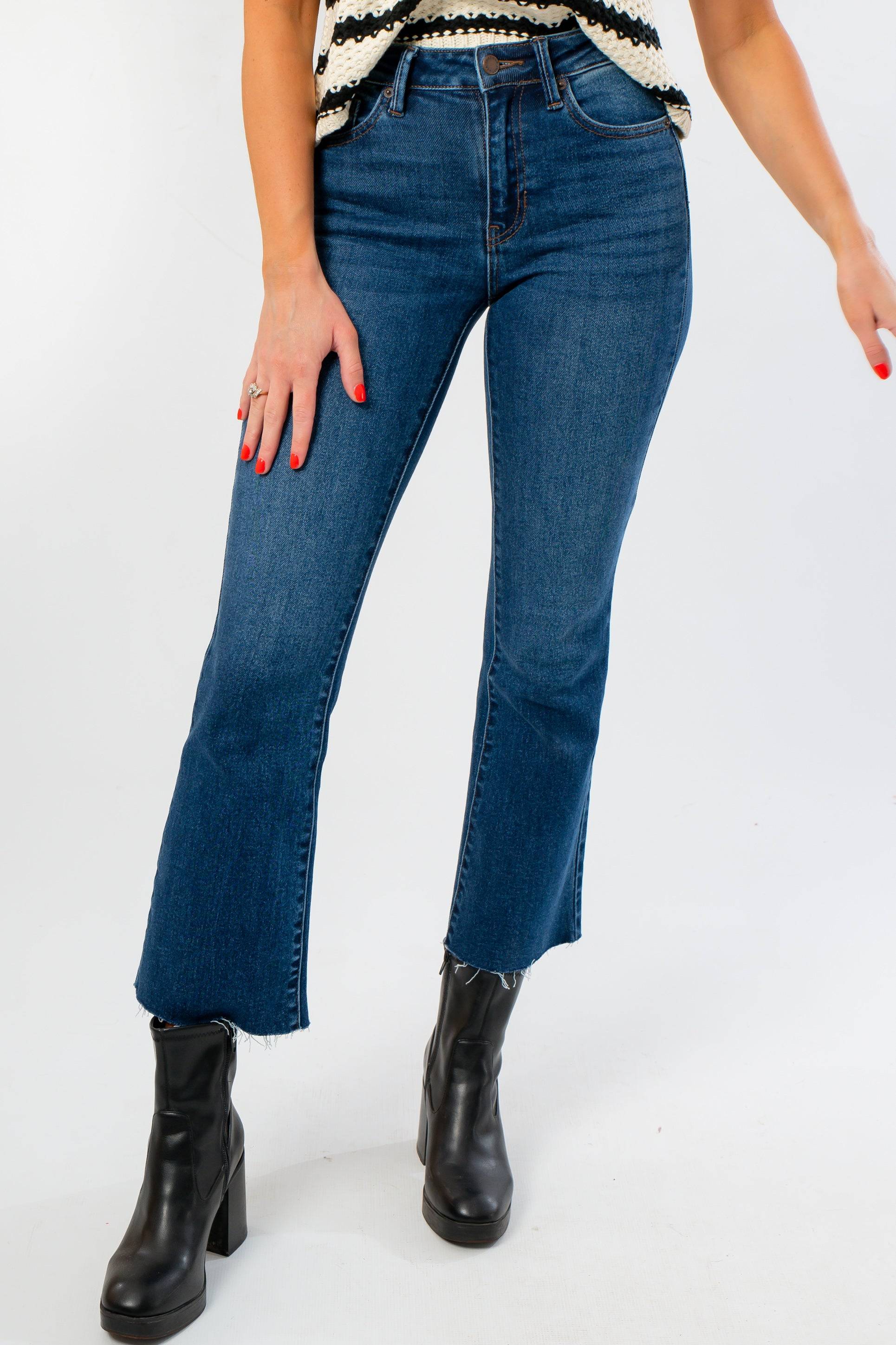On The Daily Dark Wash Crop Flare Jeans with raw hem and high waist, styled with black boots for a trendy fall denim look.