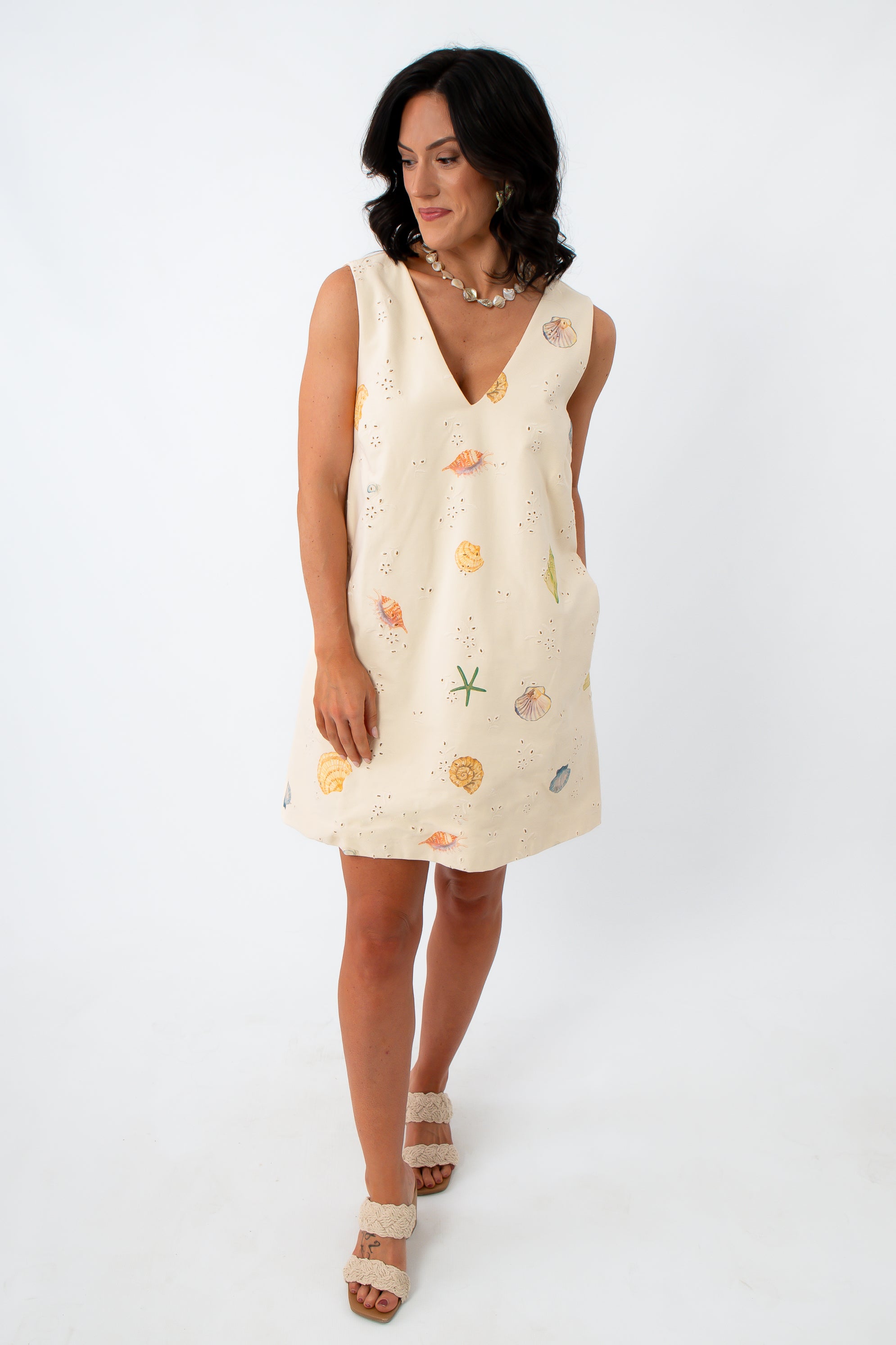 Side view of woman in Coastline Romance beach patterned shift dress with shell and starfish print, styled for summer vacation.