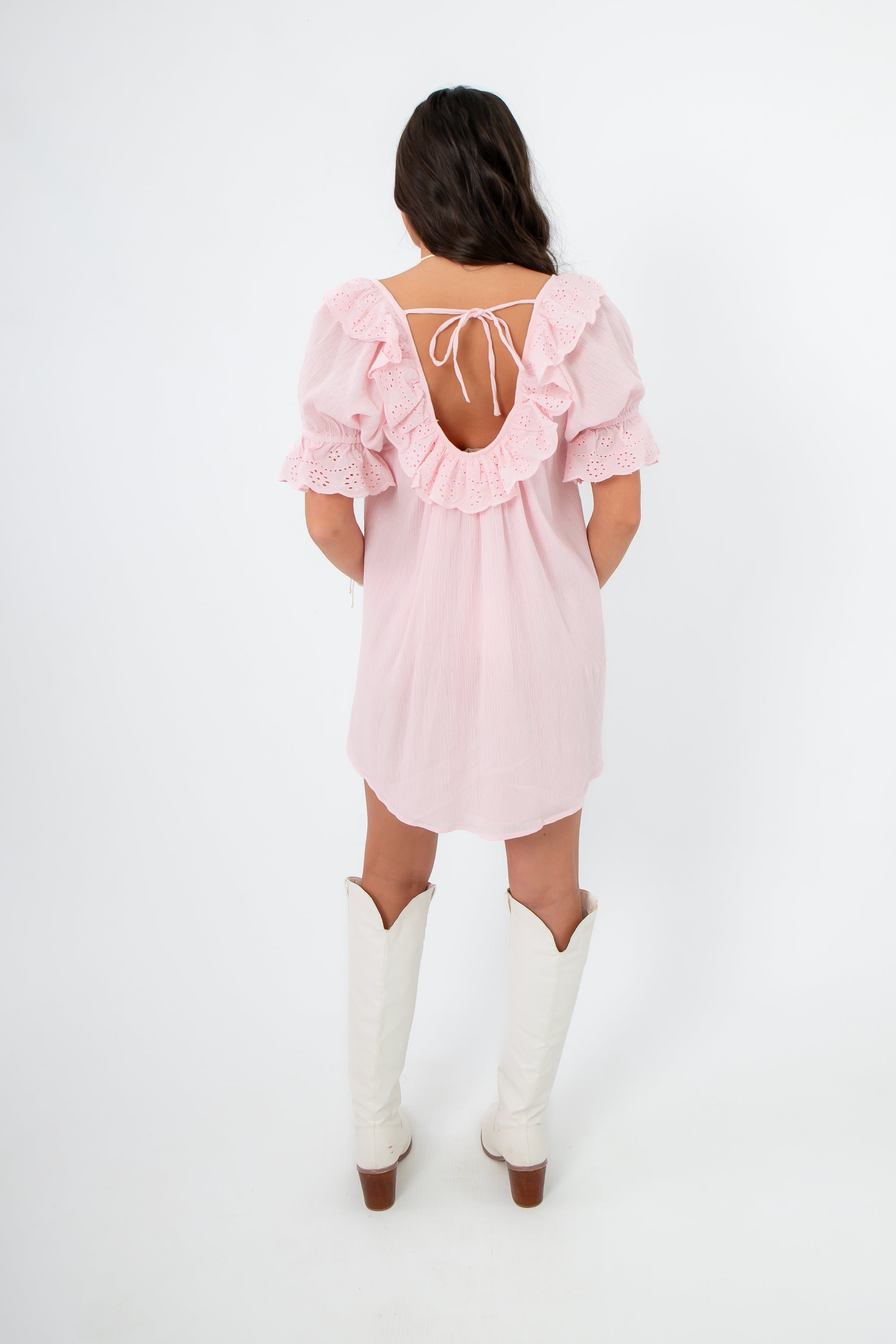 Back view of Show Me Your Mumu Pink Eyelet Toulouse Dress with open back tie detail and ruffled trim, styled for a chic summer outfit.