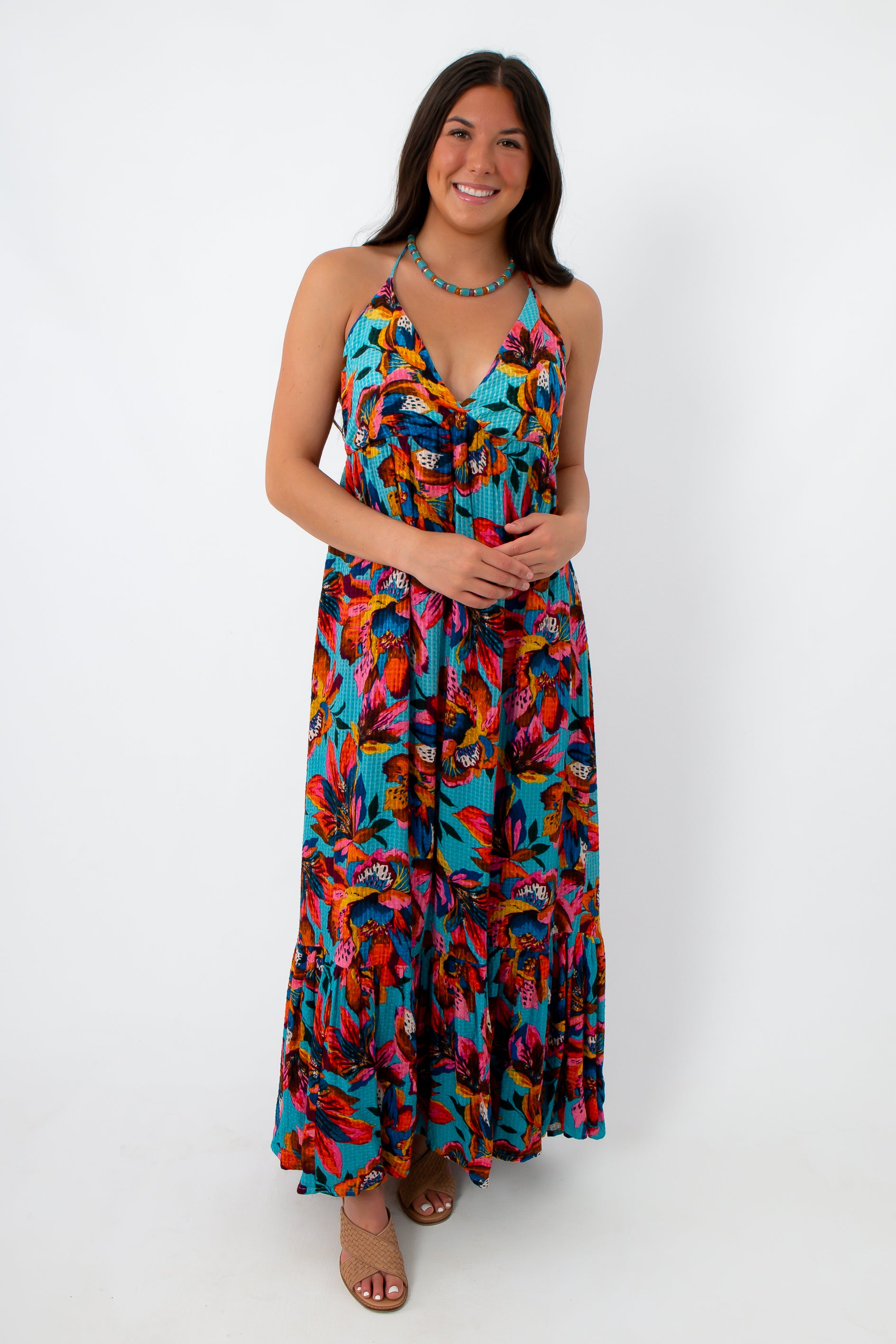 Woman in vibrant tropical print halter maxi dress with tie-back